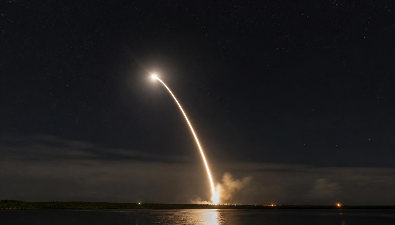 A night launch arcing over the water